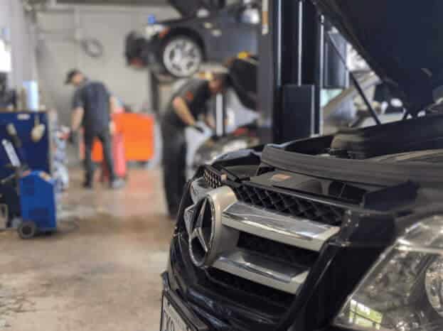 Mercedes-Benz vehicle in a repair shop with technicians working on cars