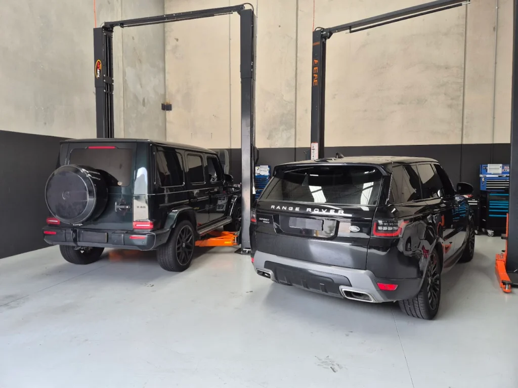 Mercedes-Benz and Range Rover vehicles on hydraulic lifts in a modern garage