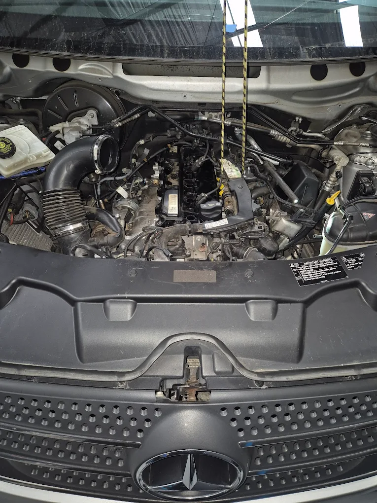 Mercedes-Benz engine compartment showing intricate components, air intake system, and diagnostic equipment