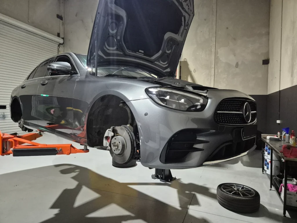 Mercedes-Benz vehicle in a garage with hood raised, undergoing maintenance