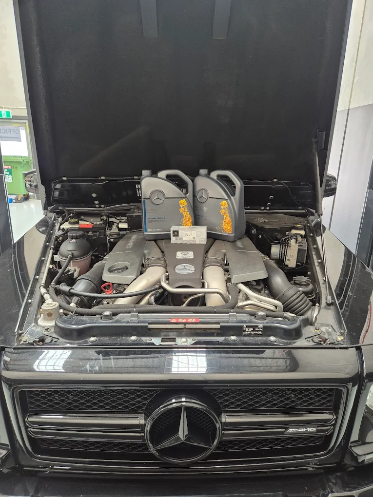 Mercedes-Benz engine bay featuring oil containers and maintenance tools
