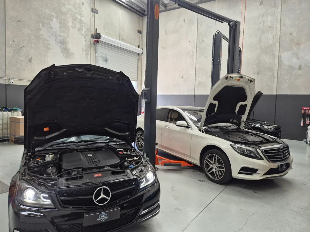 Mercedes-Benz vehicles with open hoods in a modern automotive workshop